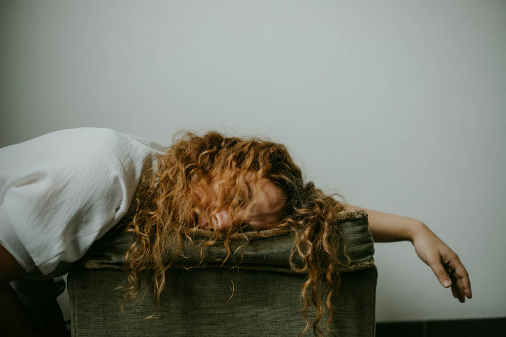 Photo of a woman lying down, exhausted with messy hair everywhere.