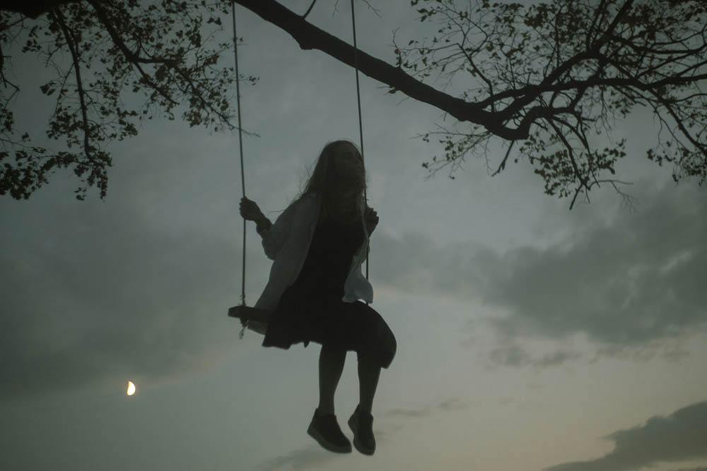 Photo of a sad girl, sitting on a swing.